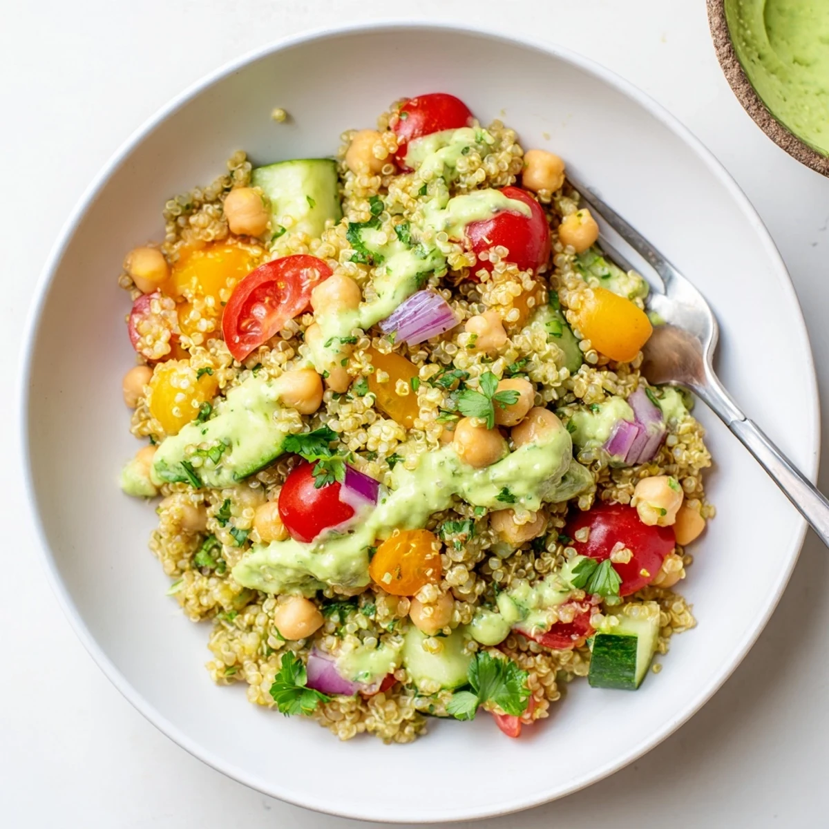 Colorful quinoa salad featuring chickpeas, crisp vegetables, and zesty avocado dressing.