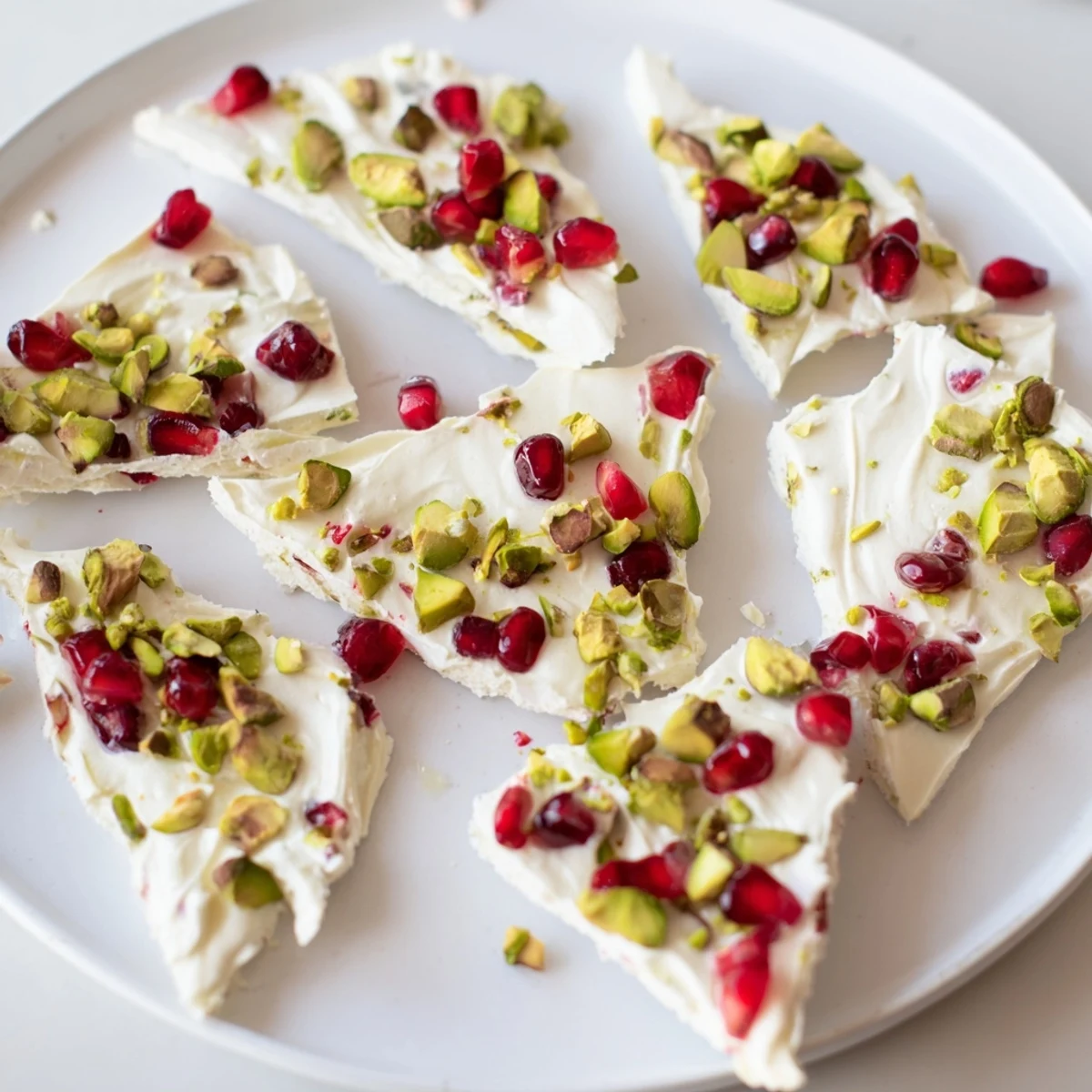 Close-up of frozen yogurt bark showcasing creamy layers and crunchy pistachios alongside sweet pomegranate arils.