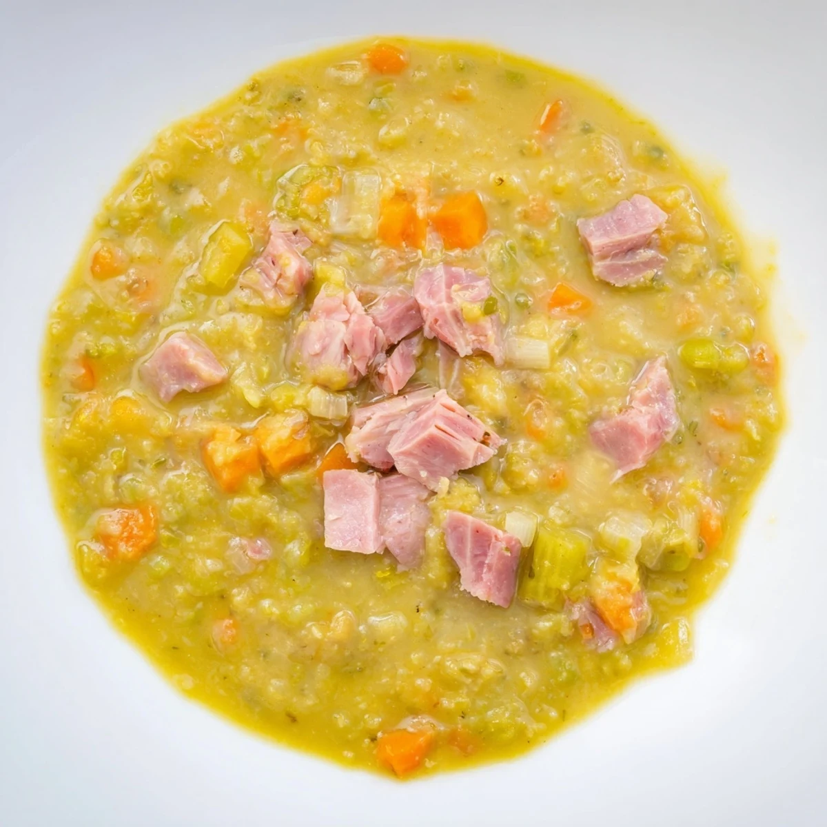 Hearty Split Pea and Ham Soup, a steaming bowl, is filled with tender peas and savory ham.