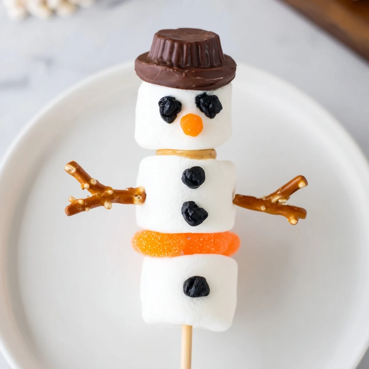 Easy, no-bake marshmallow snowman stick arrangement, inviting kids to enjoy this winter snack.