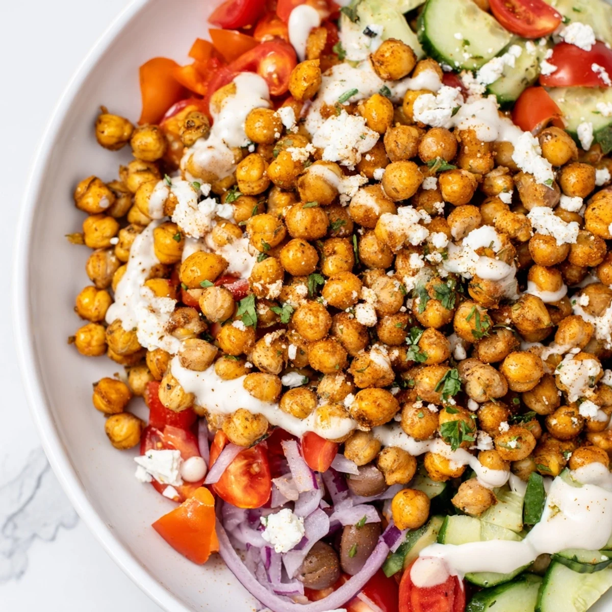 A colorful Mediterranean Chickpea Bowl featuring golden, crispy chickpeas alongside fresh, chopped vegetables.