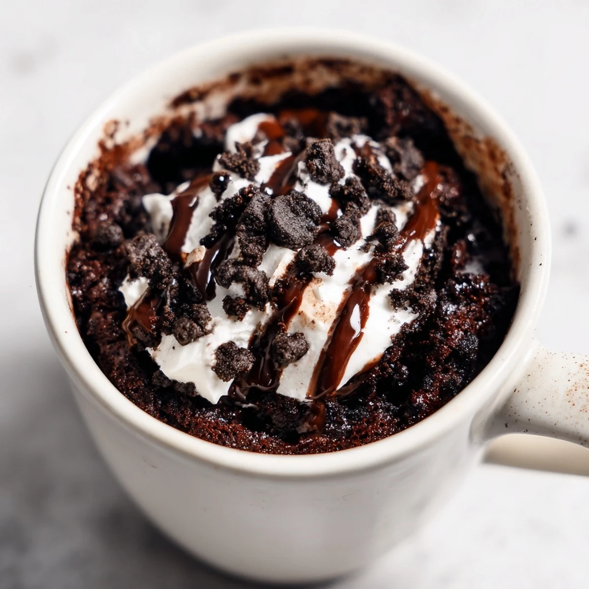 A single serving of a decadent Oreo Mug Cake, with a perfect fudgy texture, perfect for dessert.