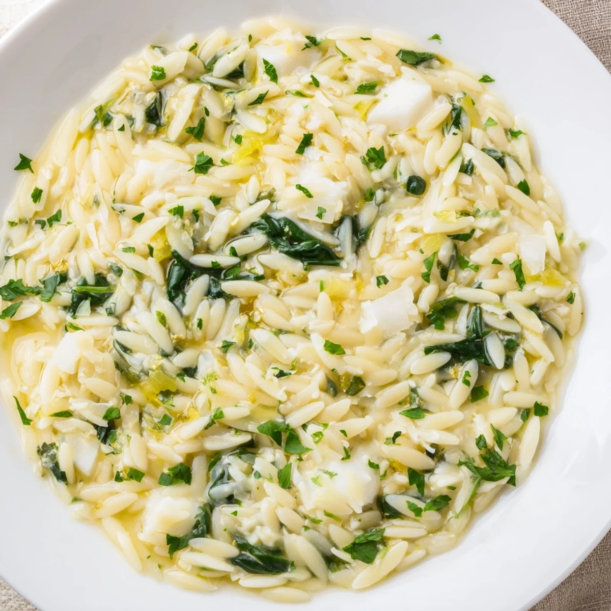 Warm, appetizing bowl of one-pot creamy orzo pasta with spinach and melted mozzarella.