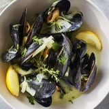 Golden mussels swimming in broth: a close-up of this classic Belgian Moules Marinière dish.