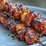 Grilled BBQ chicken pineapple kebabs with red onion and smoky glaze, perfect for summer cookouts.  