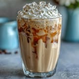 Iced Vanilla Bean Frappuccino with Coconut Whipped Cream in two tall glasses, topped with fluffy dairy-free coconut cream and vanilla bean specks.
