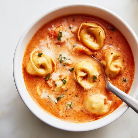 Creamy Tomato Basil Tortellini Soup in a warm bowl, garnished with fresh basil.  