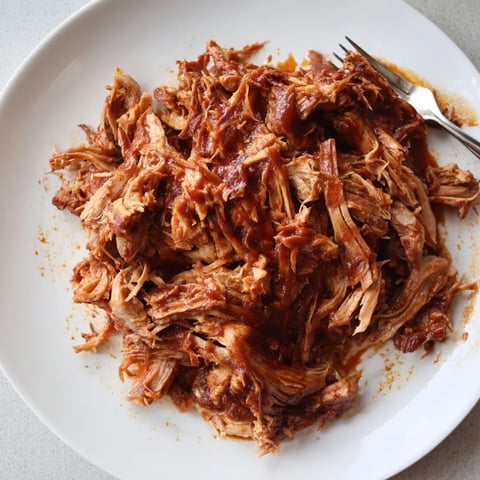 Tender Slow Cooker BBQ Pulled Pork drizzled with rich, smoky barbecue sauce.  