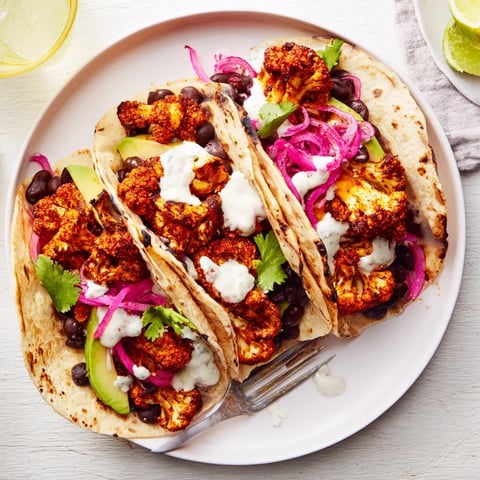 Crispy Spicy Cauliflower and Black Bean Tacos topped with avocado and fresh cilantro.