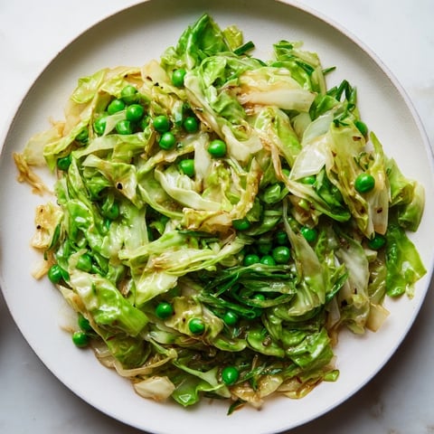 Steaming cabbage stir-fry with garlic, soy, and peas; a colorful, fragrant Asian-inspired side dish.