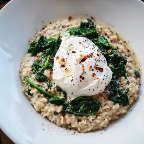 Delicious savory oatmeal with spinach and poached egg, featuring a runny yolk and vibrant greens.