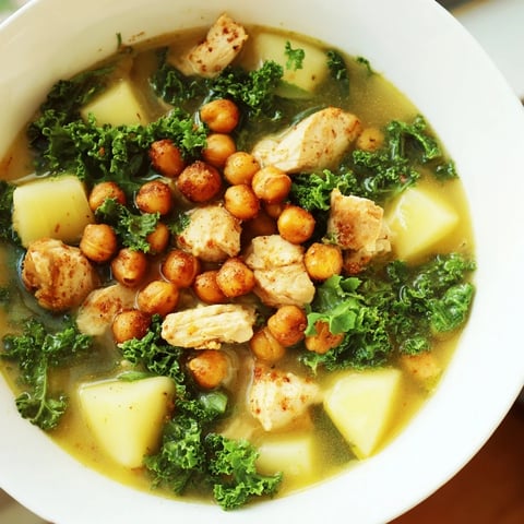 Tender chicken kale soup with chickpeas, a hearty bowl brimming with vibrant greens and golden chickpeas.