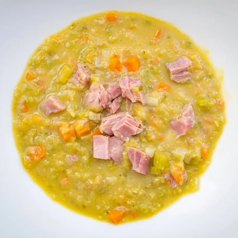 Hearty Split Pea and Ham Soup, a steaming bowl, is filled with tender peas and savory ham.