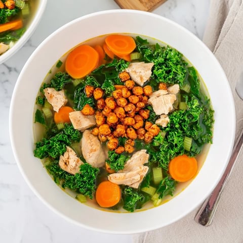 A steaming bowl of Chicken Kale Soup topped with crunchy, golden chickpeas, ready to eat.
