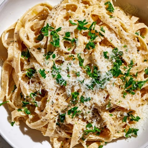 Skinny Alfredo Garlic Parmesan Snowy Pasta, a creamy, light dish glistening with grated Parmesan.