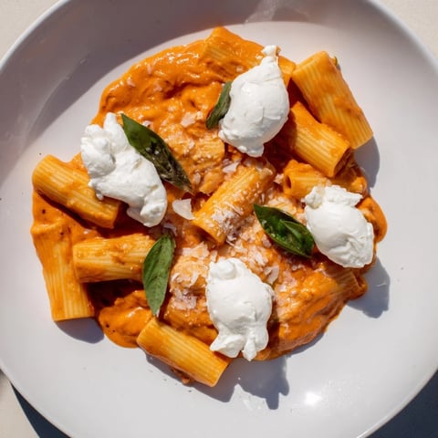 Creamy Roasted Red Pepper Santa Hat Pasta: Vibrant red sauce pasta topped with creamy white ricotta, resembling Santa hats.