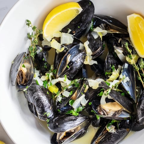Steaming Belgian Moules Marinière with fresh herbs and wine creates a delicious, savory seafood main course.