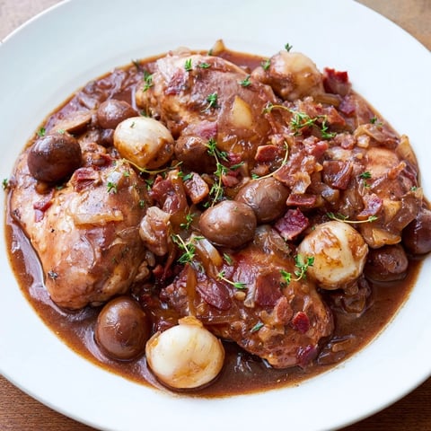 Hearty Coq au Vin, a rich French stew, features tender chicken with pearl onions and mushrooms.