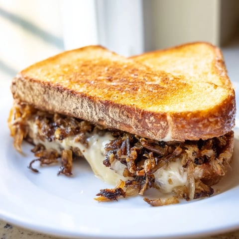 Gooey melted cheddar and mozzarella peek from golden toasted sourdough, loaded with crispy fried onions in this decadent Crispy Onion Grilled Cheese.