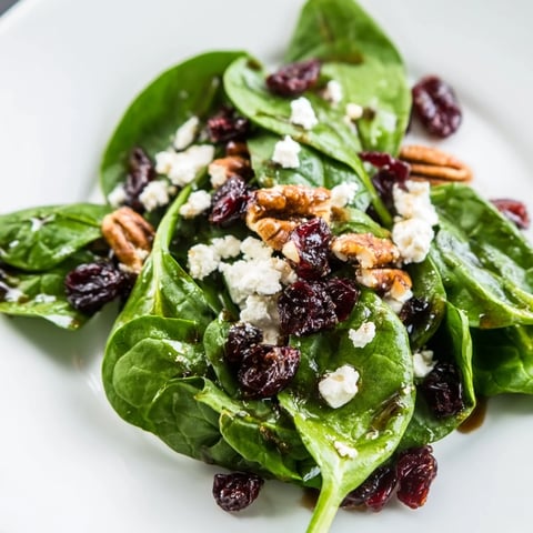 Fresh Spinach Goat Cheese Salad with creamy crumbles, sweet dried cranberries, and crunchy candied pecans tossed in tangy balsamic vinaigrette.