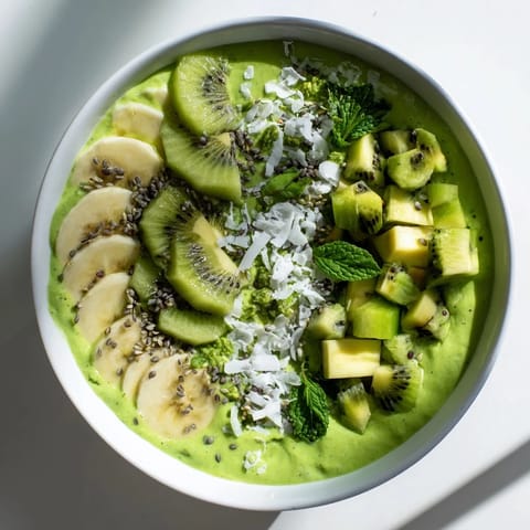 Creamy Green Smoothie Bowl with kale, avocado, and kiwi, a bright breakfast treat, beautifully garnished.