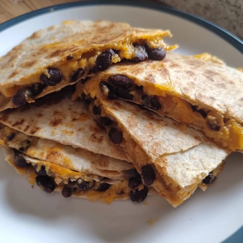 Sizzling skillet full of cheesy, folded Bean & Cheese Quesadillas, ready to be sliced and served with salsa.