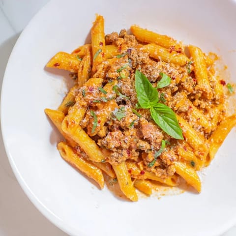 A close-up of delicious Creamy Tomato and Sausage Pasta in a skillet, with bubbling sauce visible.