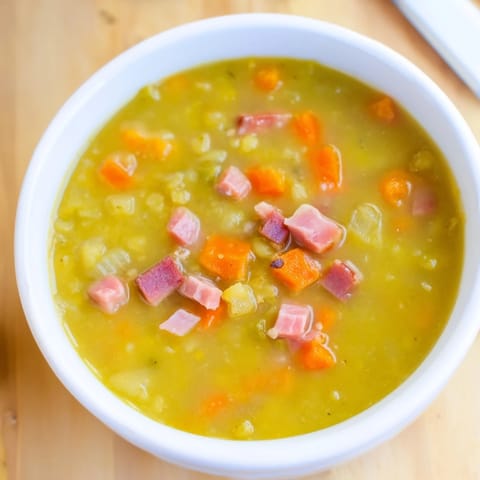 This hearty Split Pea and Ham Soup features a rich, smoky broth with diced carrots and ham pieces.