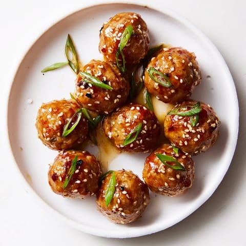 Close-up of golden brown Spicy Honey-Glazed Chicken Meatballs, coated in a sweet and spicy sauce.