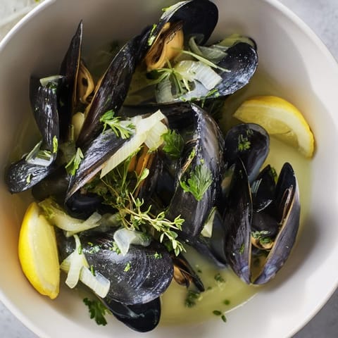 Golden mussels swimming in broth: a close-up of this classic Belgian Moules Marinière dish.