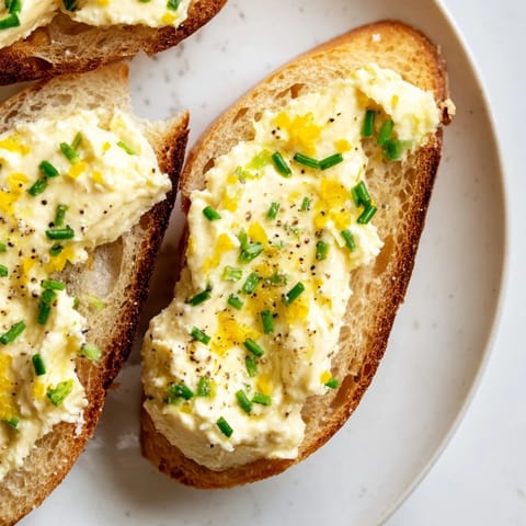 Crisp baguette slices with vodka-infused butter, black pepper, and chives, perfect for cocktail party finger food.