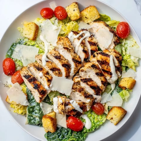 A close-up of the Yogurt Caesar Grilled Chicken Salad featuring golden grilled chicken, fresh romaine, and shaved Parmesan.  