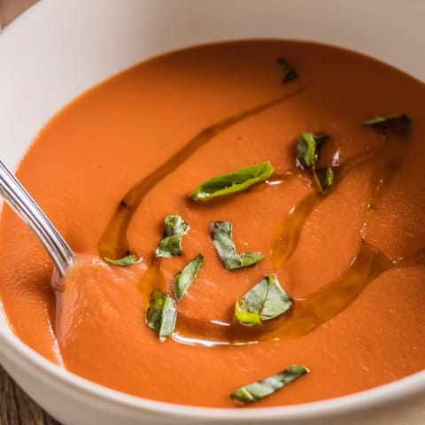 Creamy Tomato and Basil Soup served hot, perfect for dipping a grilled cheese sandwich or crusty sourdough bread on the side.