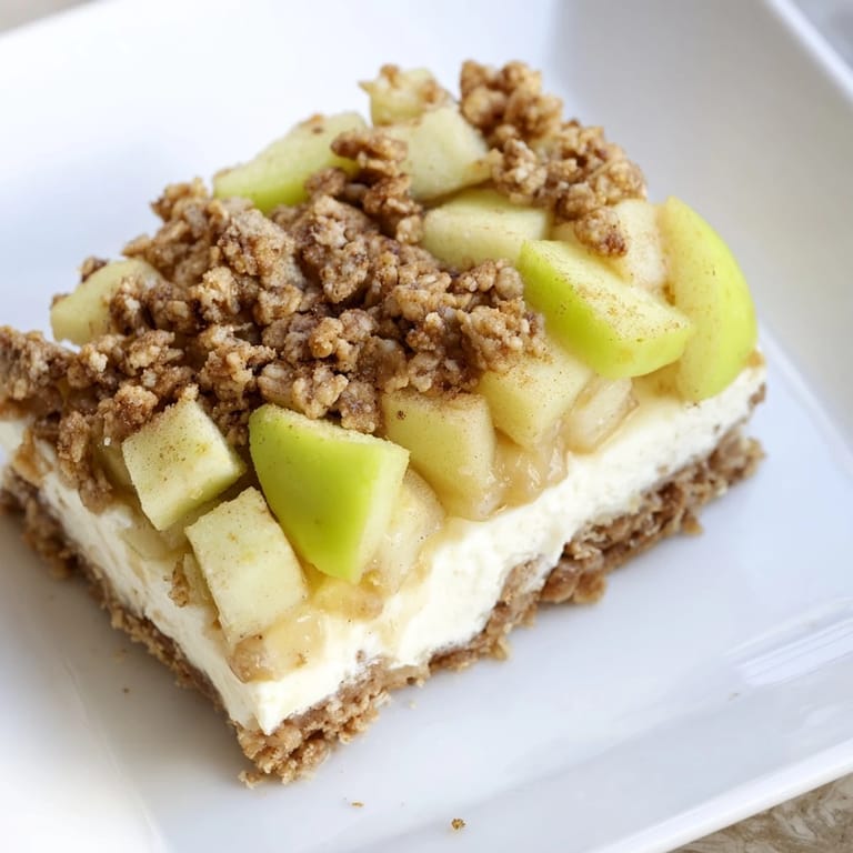 Close-up of baked Apple Crisp Cheesecake Bars, showing layers of crumble topping and apple filling.