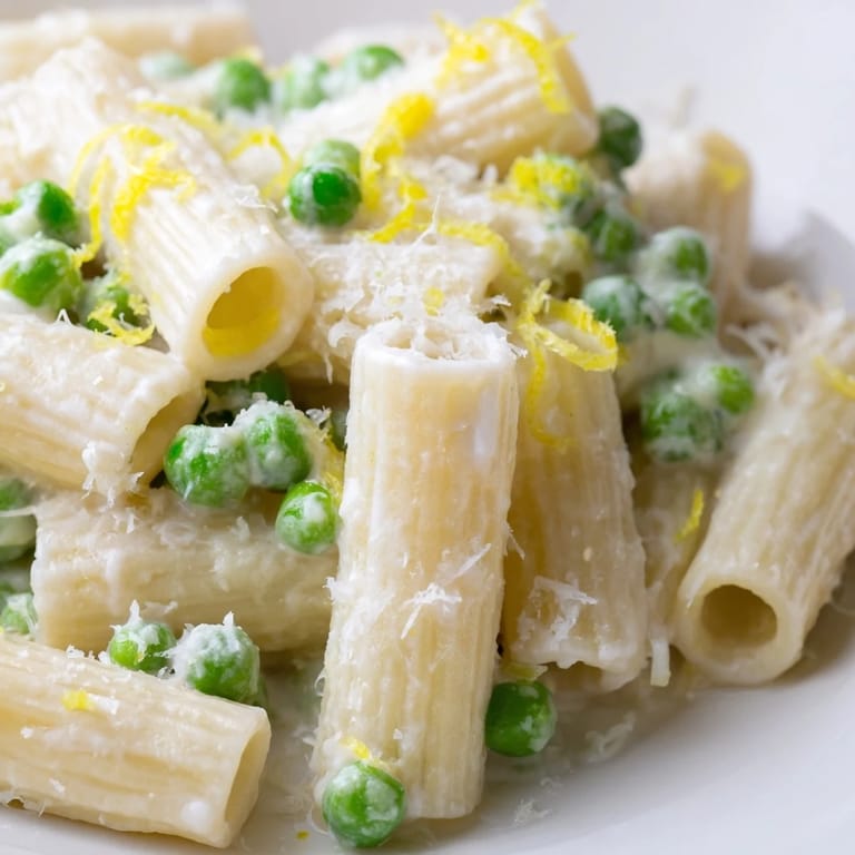 Spring pea and lemon ricotta pasta served with a lemon wedge, ready for a quick vegetarian dinner.
