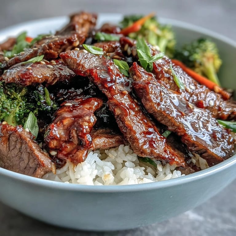 Close-up of tender Teriyaki Beef Bowl beef slices glistening in homemade sauce over sautéed crisp vegetables.