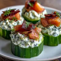 Cucumber bites topped with creamy dill cream cheese and smoked salmon, garnished with capers and fresh dill. Perfect for elegant appetizers or summer parties.